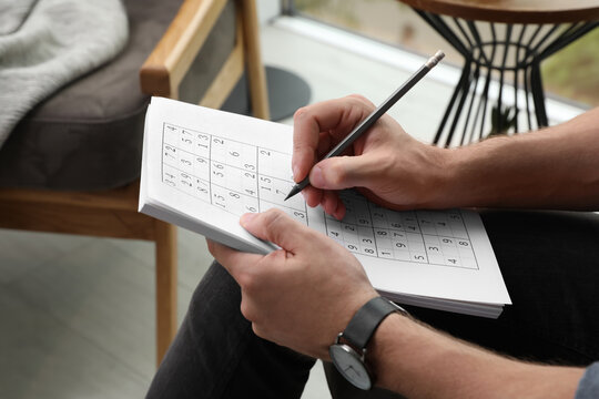 Man solving sudoku puzzle at home, closeup