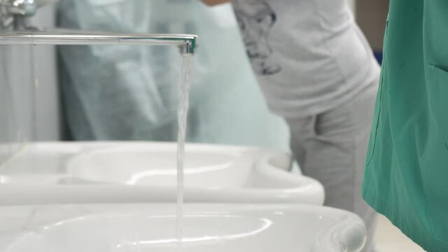 Doctors wash their hands under water and soap before undergoing surgery at a hospital to remove cancer.