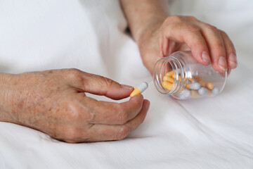 Pills in wrinkled hands of elderly woman. Medication in capsules, taking sedatives, antibiotics or vitamins in old age