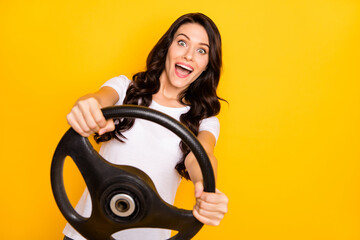 Portrait of pretty cheerful amazed wavy-haired girl holding steering wheel having fun isolated over...