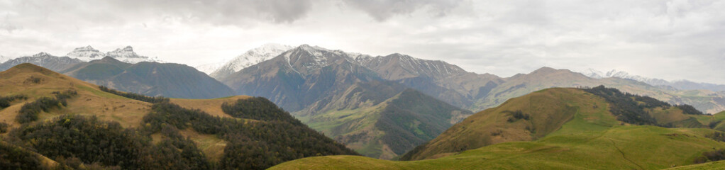 Aktoprak is a pass, known since ancient times, connecting the Baksan and Chegem gorges. Panorama view of green hills covered with vegetation and high mountains. Kabardino-Balkaria, Russia