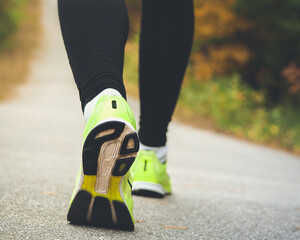 young fitness women legs running at forest trail close up on shoe