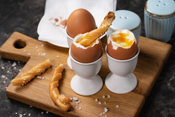 Soft-boiled chicken egg for breakfast with toast against dark background