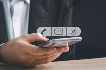 Fototapeta premium CONTACT US, Customer support, Customer service concept. Businessman holding mobile smartphone with ( mail,phone,email ) icon ,copy space.