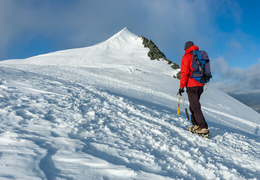 Mountaineer climbs a snowy peak in swiss Alps.