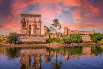 Fototapeta na wymiar Incredible orange sunrise at the temple of Philae, a Greco-Roman construction seen from the Nile river, a temple dedicated to Isis, goddess of love. Aswan. Egyptian