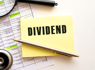 DIVIDEND text on a sticker on your desktop. Pen and magnifier.