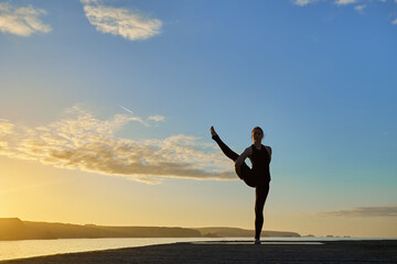 Fototapeta na wymiar Advanced yoga posture in silhouette in a sunset
