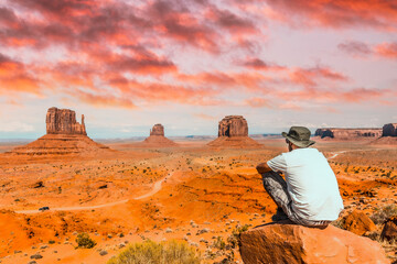 Fototapeta na wymiar A young boy with white t-shirt sitting in the center of the photo on a stone in the Monument Valley National Park in the visitor center. Utah