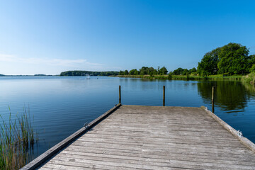 wooden dock leads out into a calm lake with dark blue water
