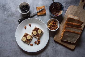 Healthy breakfast food ingredients bread, peanut butter, bananas, almonds, nuts, dry fruits milk. Concept of wholesome and healthy food.