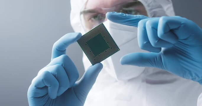 Close-up of repairman in protective uniform holding computer processor, removing chip CPU. Technologies and developments concept. Technician engineer looking at detail for gadget. 