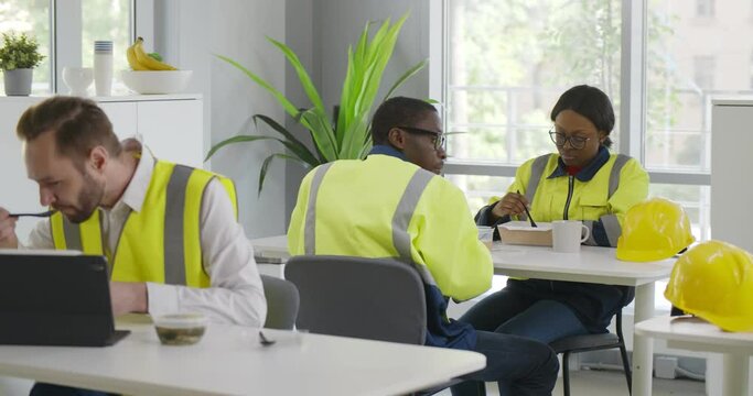 Diverse warehouse workers eating meal in industrial canteen