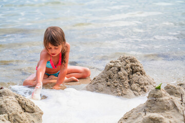 Portrait of beautiful young girl playing on sea beach. Summer holiday and vacation concept. Horizontal image.