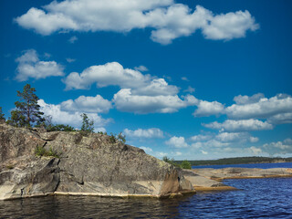White clouds over the water. Rocky shore. Russia. Karelia. Ladoga lake.