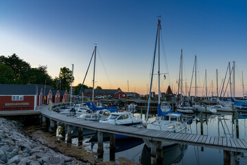 the picturesque small marina at Lundeborg with many sailboats and colorful hosues at sunset