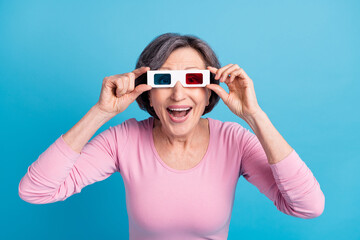Photo of happy excited crazy cheerful smiling mature woman watching movie in 3d glasses isolated on blue color background