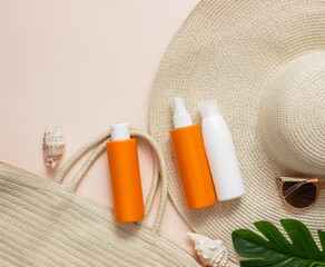 Travel accessories, sunscreen in plastic bottles,sunglasses, beach bag,straw hat,tropical leaves .Travel and vacation concept at sea . Flat lay. top view.