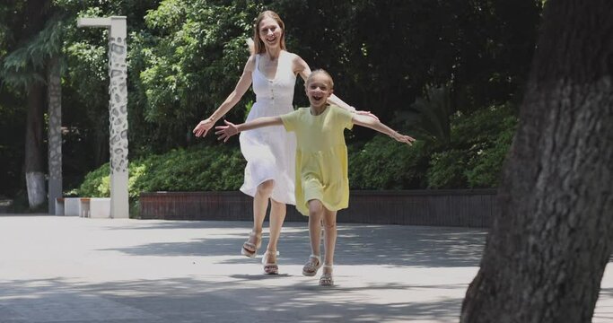 Happy family walking in summer park. Young Caucasian Mother and daughter seven years old spending time together. 4k Slow motion