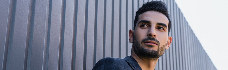 Low angle view of arabian man looking away near fence outdoors, banner