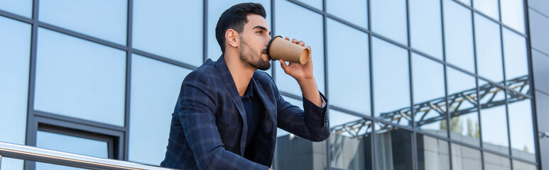 Young arabian businessman drinking coffee near building, banner