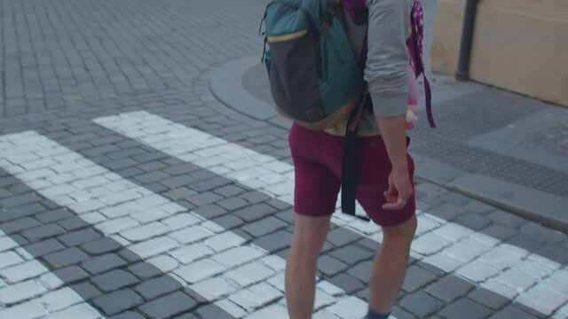 An active father uses a carrier to transport the child. Move on a pedestrian crossing with a child in the city. Camera movement.
