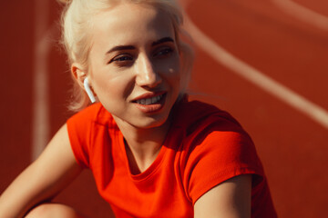 close-up portrait of a beautiful blonde who is sitting on a jogging track