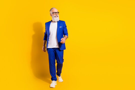 Full length body size view of attractive chic cheerful man walking isolated over bright yellow color background