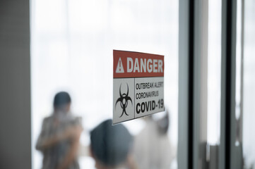 Coronavirus 19 danger sign in front of control area. Medical team who are vaccinating give people in the laboratory. Concept of preventing the spread of COVID-19.