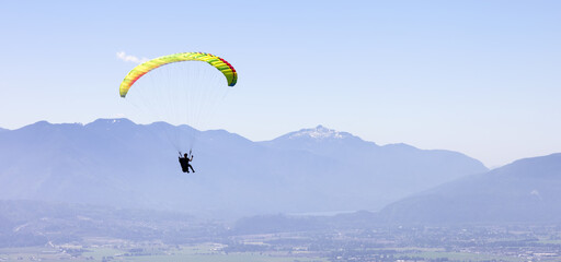 Adventurous Woman Flying on a paraglider around the Canadian Mountain Landscape. Harrison Mills...