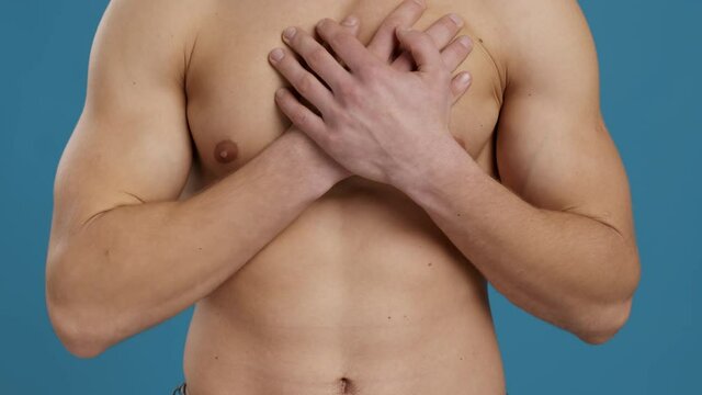 Heart failure. Young unrecognizable muscular man suffering from pain in heart, touching his muscular chest