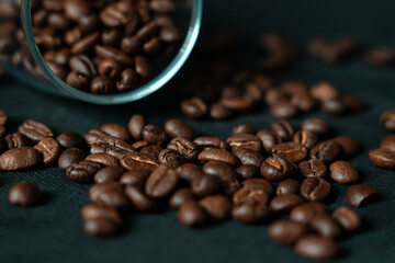 Dark roasted coffee beans with glass on black background