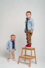 Two brothers on the white background making funny faces - blonde caucasian boys spending time together