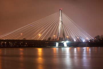 Fototapeta na wymiar The Świętokrzyski bridge at night against the Vistula river