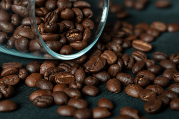 Obraz premium Dark roasted coffee beans with glass on black background
