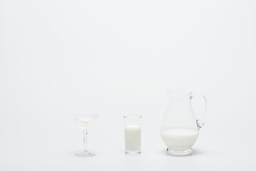 tasty macaron in dessert dish near glass of milk and jug on white