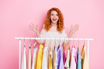 Photo portrait of red haired girl amazed doing shopping in boutique choosing clothes overjoyed isolated pastel pink color background