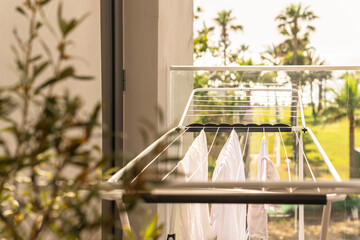 Hanging laundry on balcony on the drying rack opposite sea and palm trees view at sunset sunshine