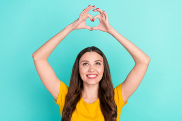 Fototapeta na wymiar Photo of optimistic young lady show heart by hands look up wear yellow t-shirt isolated on vivid teal color background