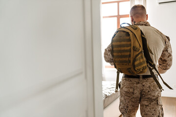 White military man wearing uniform standing with backpack at home