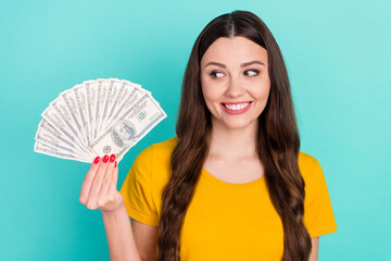 Photo of joyful millennial lady hold look dollars wear yellow t-shirt isolated on vivid teal color background