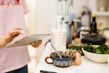 Black woman using tablet computer while cooking in kitchen at home