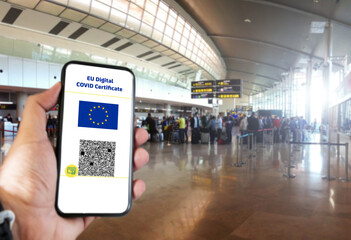 EU Digital COVID Certificate with the QR code on the screen of a mobile held by a hand with blurred...