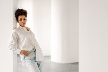 Young black woman leaning on wall and looking at camera