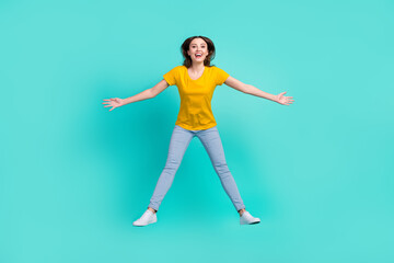 Fototapeta na wymiar Full body photo of joyful young lady jump wear yellow t-shirt jeans isolated on teal color background