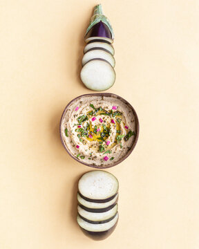 Bowl with Baba ghanoush dish on table with eggplants