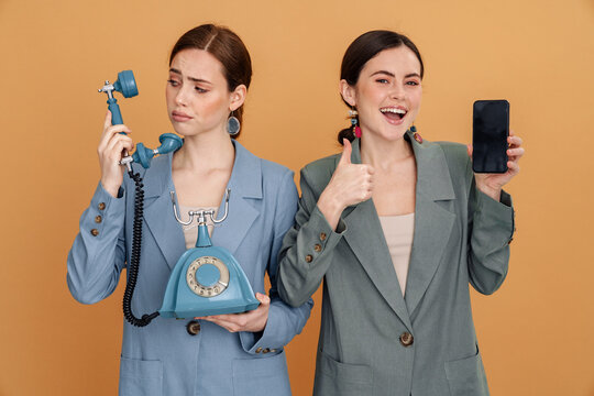 Young two women posing with retro phone and smartphone - Powered by Adobe
