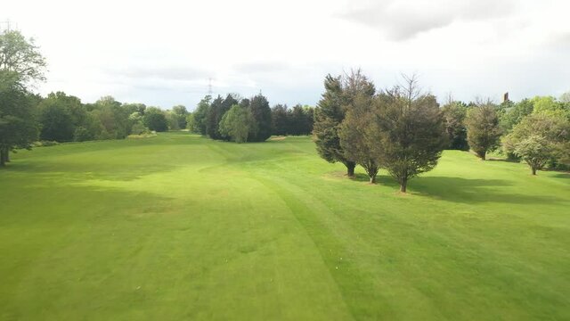 Fast flying over prepared golf course. Shortly cut lawn invites to play. Forwards reveal of sports area