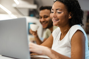 Middle eastern man and woman smiling while working with laptop together