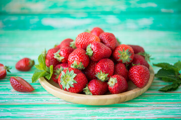 Fresh red strawberries in a plate on a rustic background, seasonal summer berries